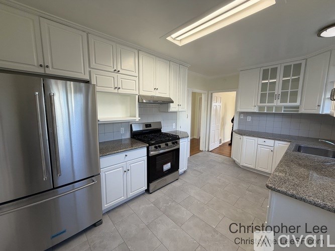 A kitchen with white cabinets and a stainless steel refrigerator.