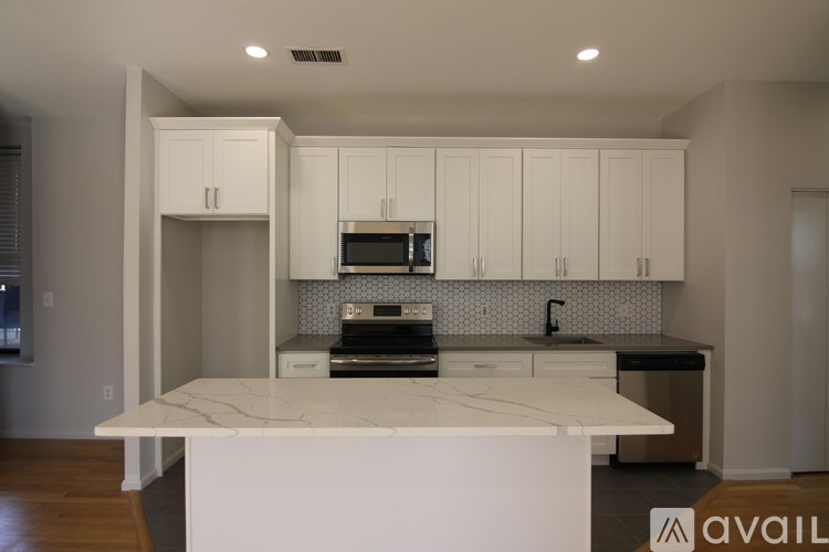 A kitchen with white cabinets and a marble island.