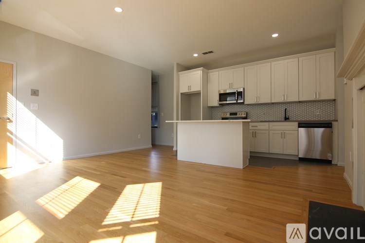 A kitchen with white cabinets and a wooden floor.