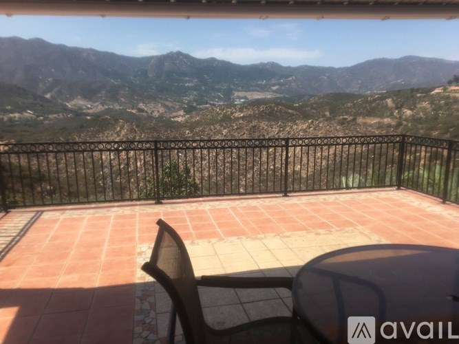 A balcony with a chair and a table overlooking a mountainous landscape.