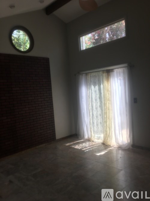 A room with a round window and a curtain with a view of trees outside.