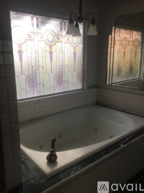 A bathroom with a white bathtub and a stained glass window.