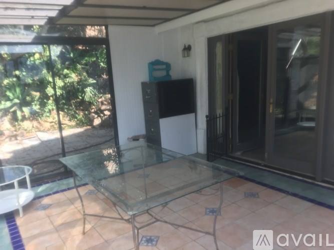 A glass table is in the middle of a patio.