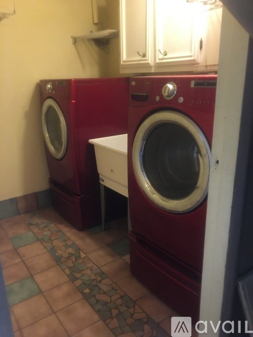 A red washing machine sits next to a white one.