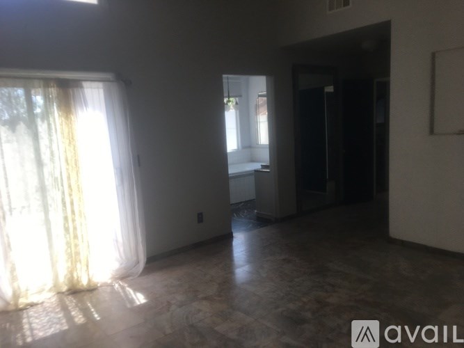 A room with a large window and a door leading to another room.