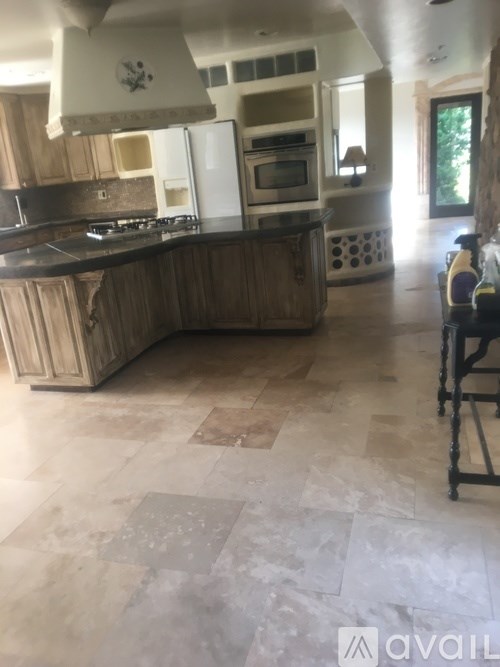 A kitchen with a tile floor and wooden cabinets.