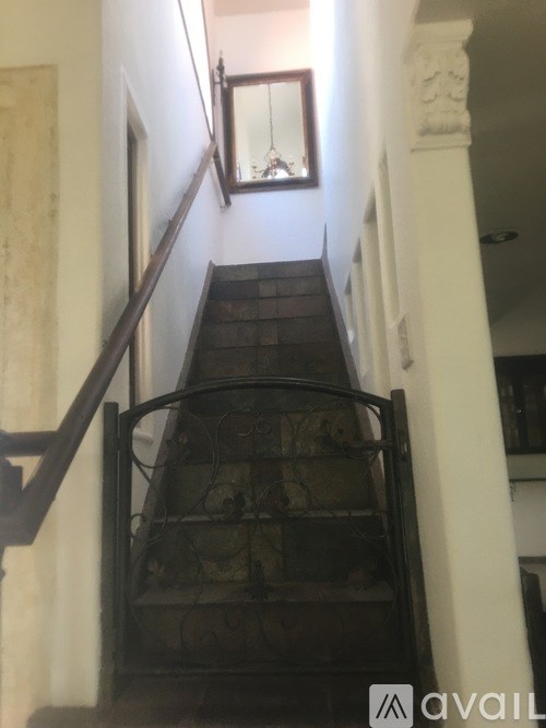 A staircase with a black metal railing and a mirror on the wall.
