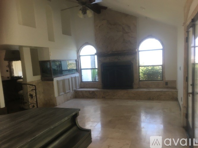 A living room with a stone fireplace and a flat screen TV.
