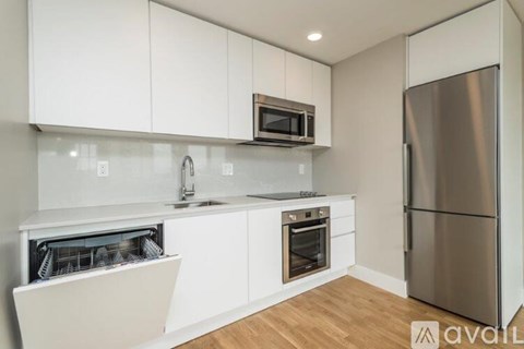 A kitchen with white cabinets and a stainless steel refrigerator.
