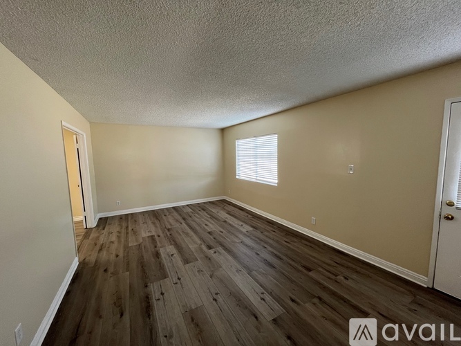 A room with wooden flooring and a door on the right.