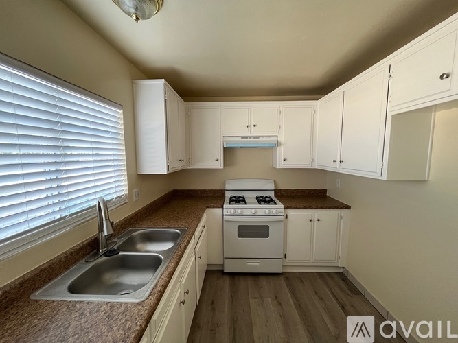 A kitchen with white cabinets and a stove top oven.