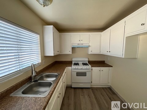 A kitchen with white cabinets and a stove top oven.