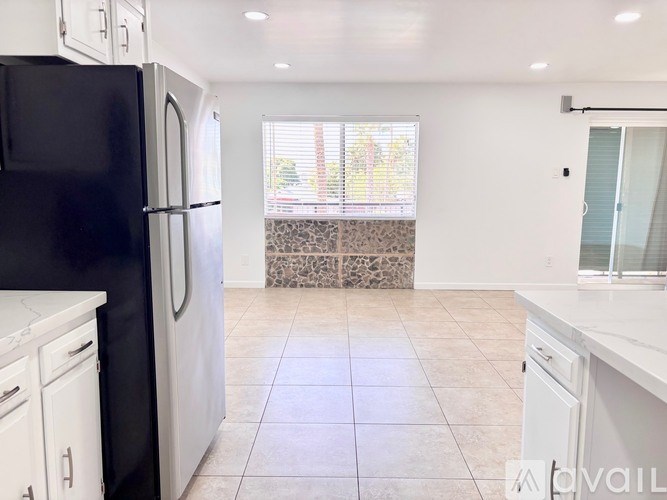 A kitchen with black and white appliances and white cabinets.