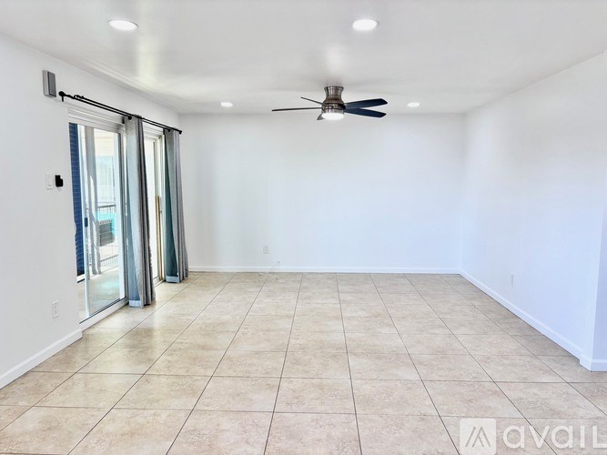 A spacious room with a ceiling fan and sliding glass doors.