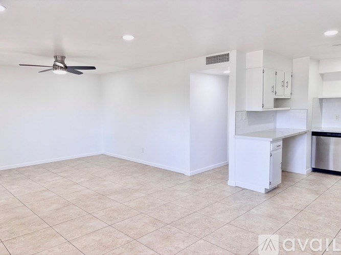 A room with a fan, a fridge, and a cabinet.
