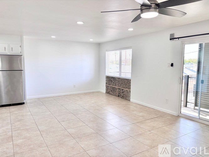 A spacious room with a ceiling fan and a stainless steel refrigerator.