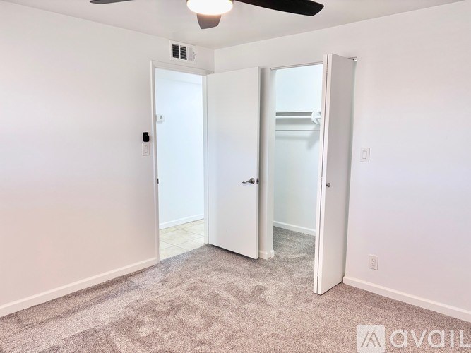 A room with a carpeted floor and a ceiling fan.