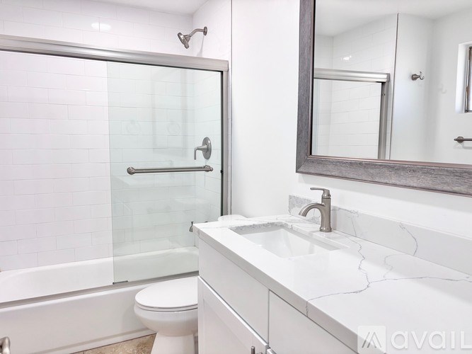 A white bathroom with a toilet, sink, and mirror.