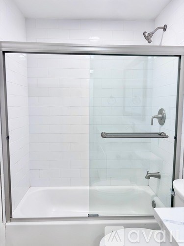 A white tiled bathroom with a glass shower door.