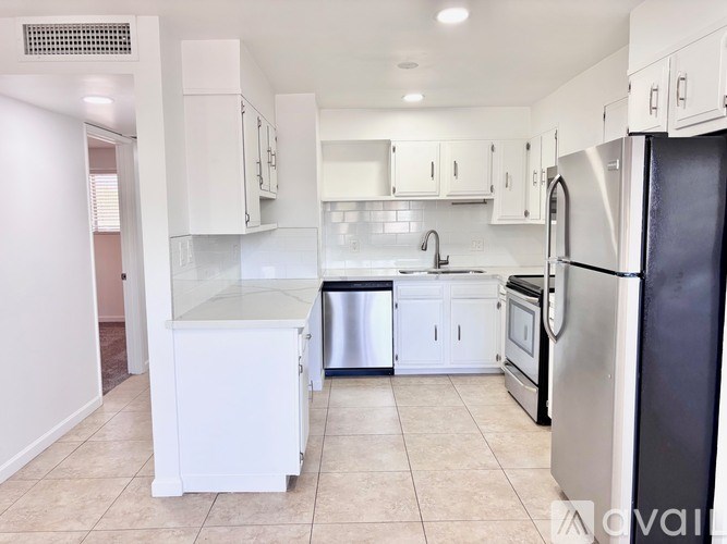 A kitchen with white cabinets and a black refrigerator.