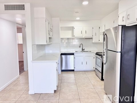 A kitchen with white cabinets and a black refrigerator.
