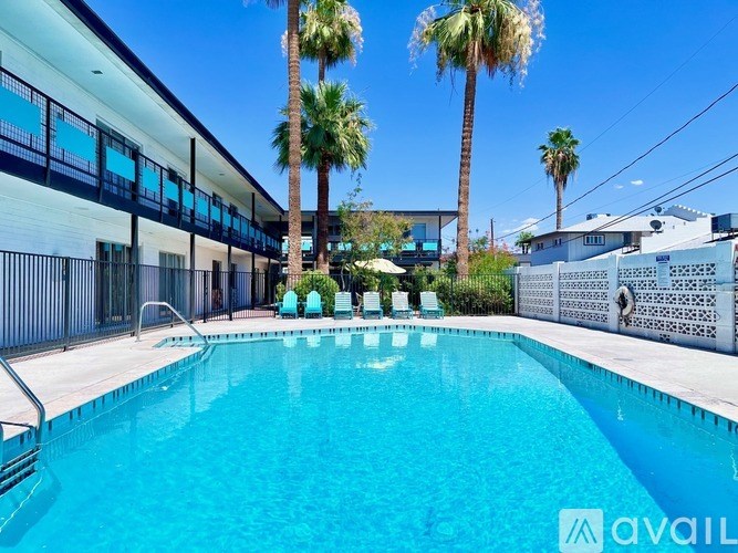 A pool surrounded by palm trees and a building with a balcony.