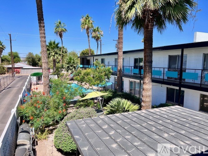 A sunny day in a courtyard with a building and palm trees.