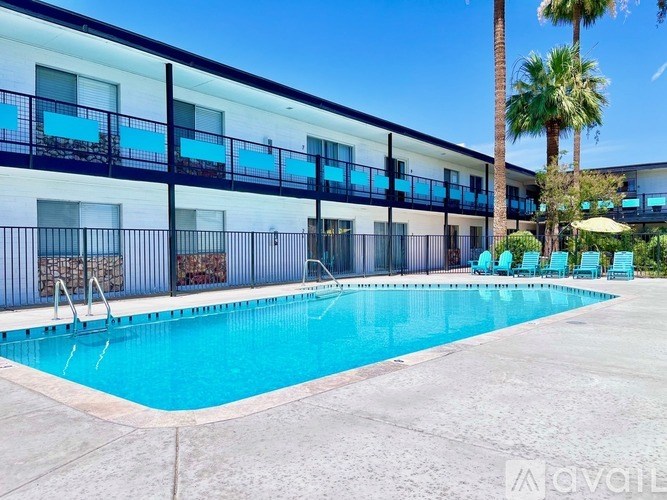 A pool in front of a building with a balcony.