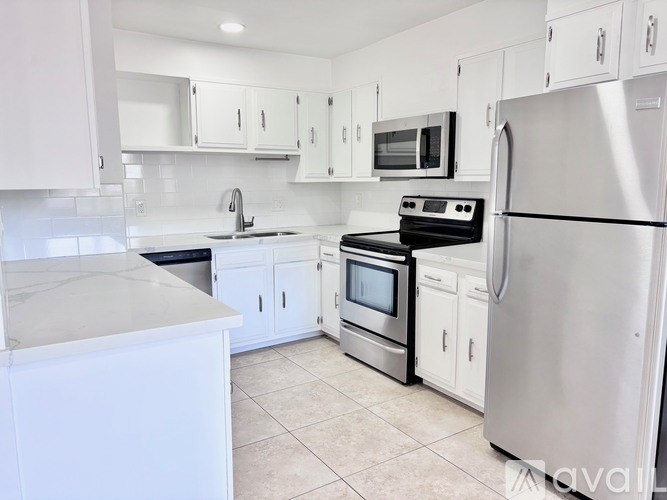 A kitchen with white cabinets and appliances.