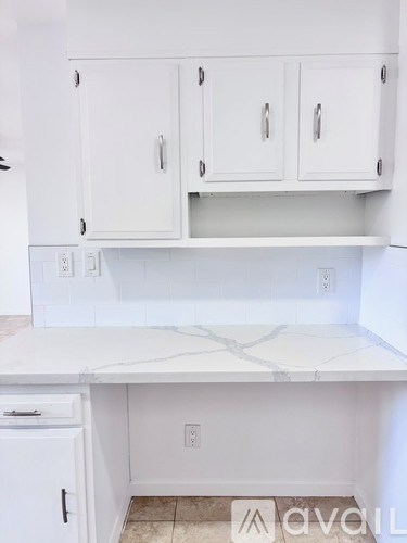 A kitchen with white cabinets and a marble countertop.