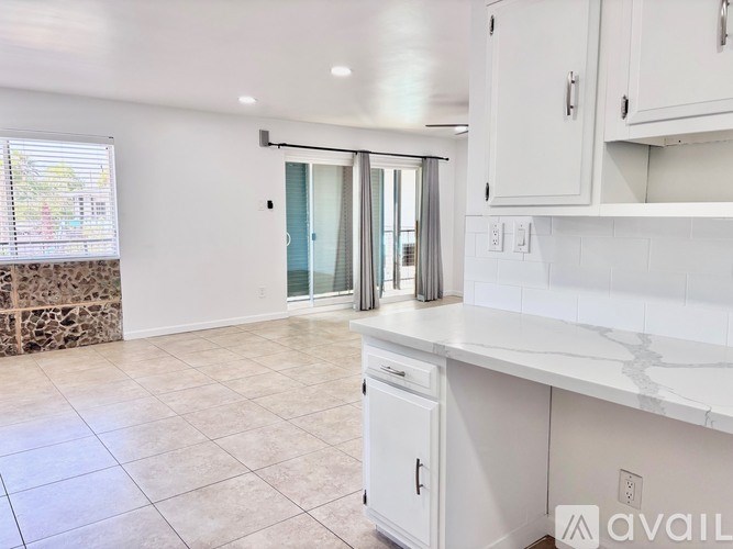 A kitchen with white cabinets and a marble countertop.