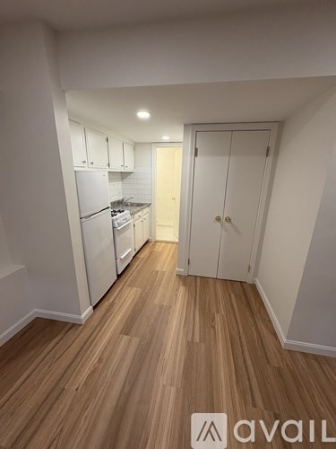 A kitchen with white cabinets and a wooden floor.