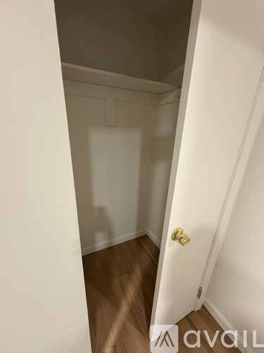 A white door with a gold handle is in a room with wooden floors.