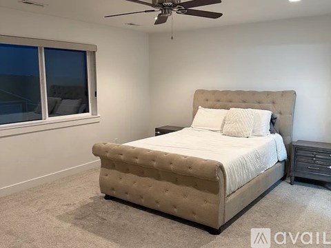 A bedroom with a large bed and a ceiling fan.