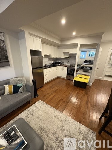 A modern kitchen with wooden floors and a grey sofa with a throw pillow.