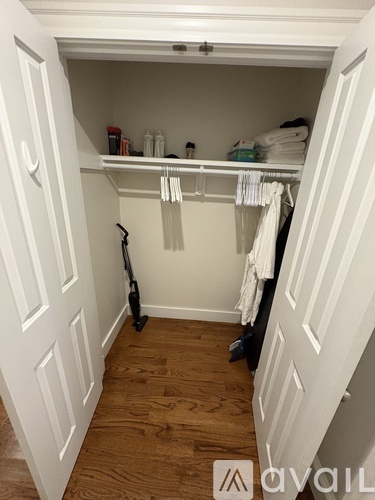 A white closet with a black vacuum cleaner on the floor.