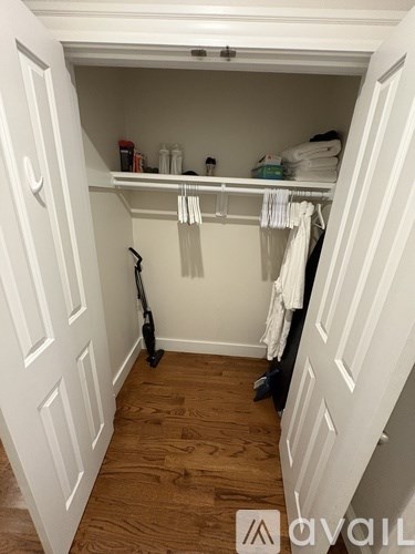 A white closet with a black vacuum cleaner on the floor.