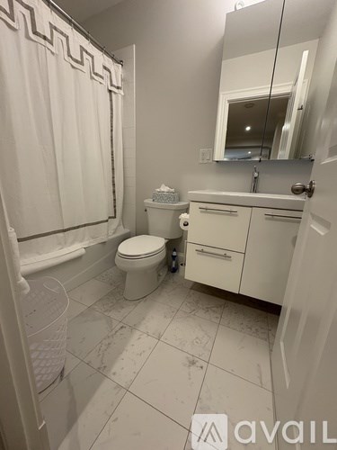 A white bathroom with a toilet, sink, and shower.
