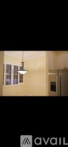 A kitchen with a hanging light fixture and a refrigerator.
