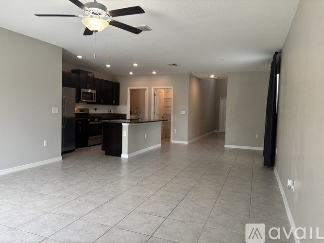 A spacious kitchen and living room with a ceiling fan and tiled flooring.