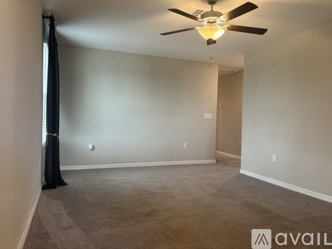 A room with a ceiling fan and carpeted floor.