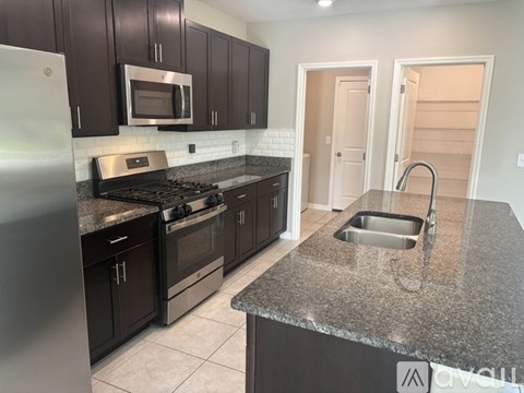 A kitchen with dark brown cabinets and a granite countertop.