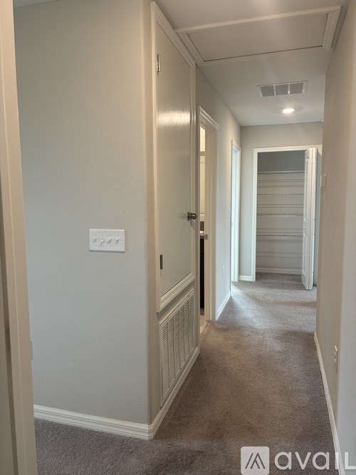 A hallway with a carpeted floor and white walls.