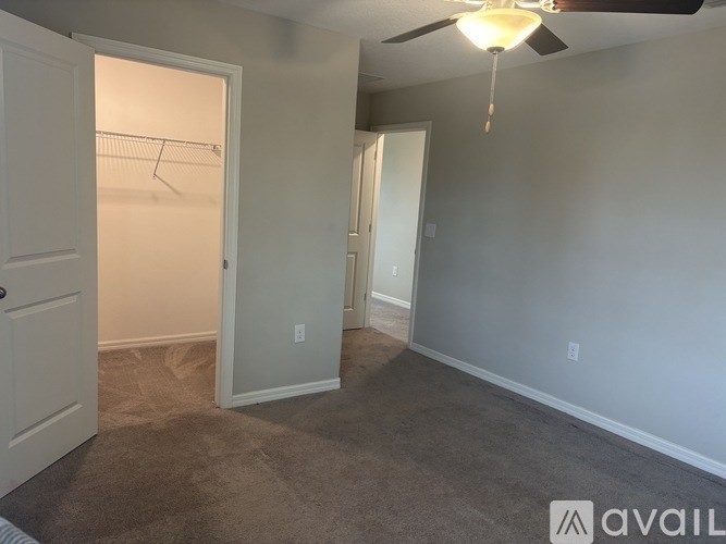 A room with a ceiling fan and a door leading to another room.
