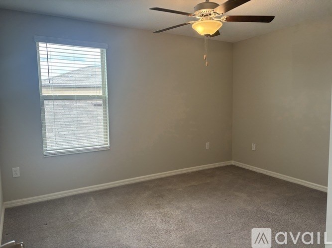A room with a ceiling fan and a window with blinds.
