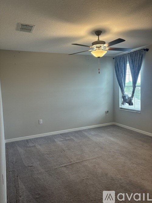 A room with a ceiling fan and carpeted floor.