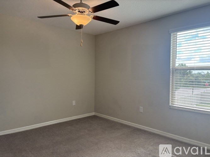 A room with a ceiling fan and a window with blinds.