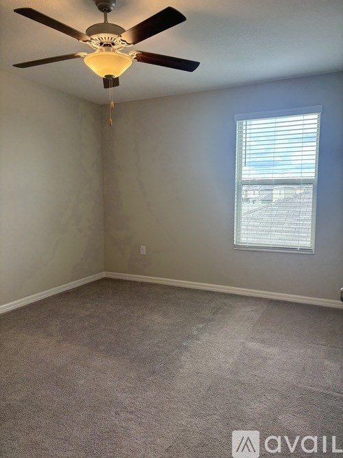 A room with a ceiling fan and a window with blinds.