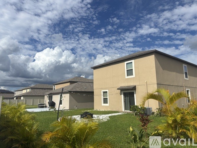 A house with a lawn and palm trees in front of it.