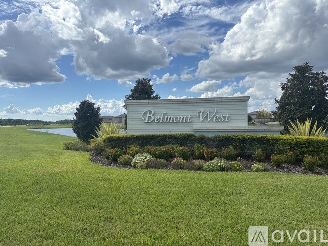 A sign that says Belmont West is in front of a grassy area.